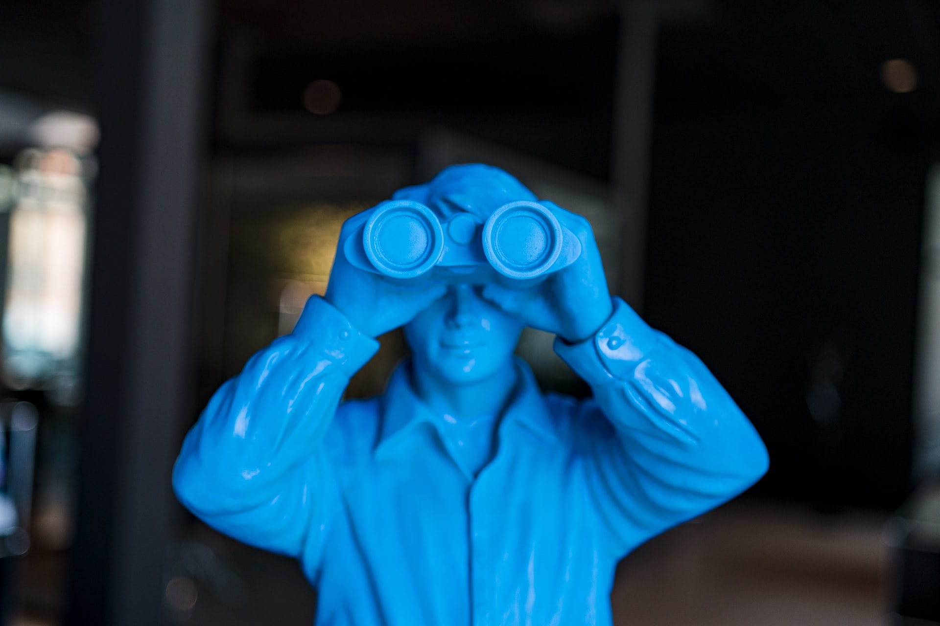 Blue toy army soldier looking out of the screen with plastic binoculars