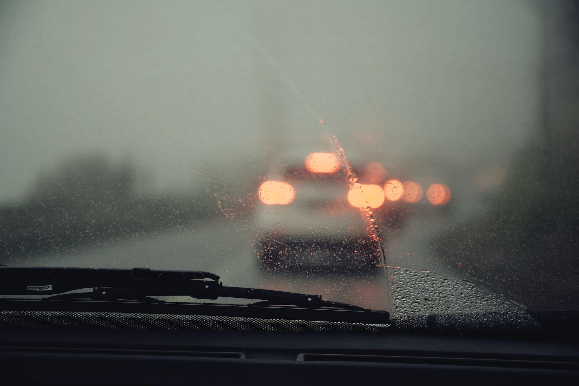 Rain on a windscreen with wipers trying to clear the view of the road ahead