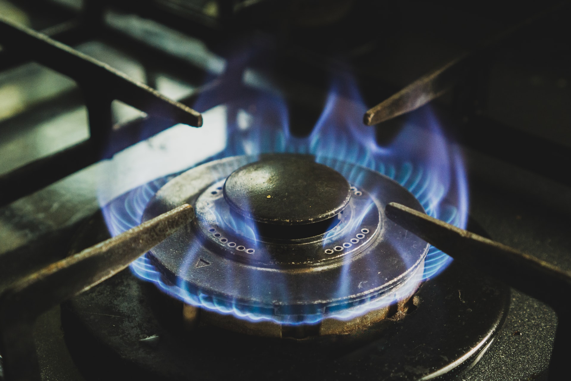 A gas burner on a hob being lit to show blue flames ready to cook on
