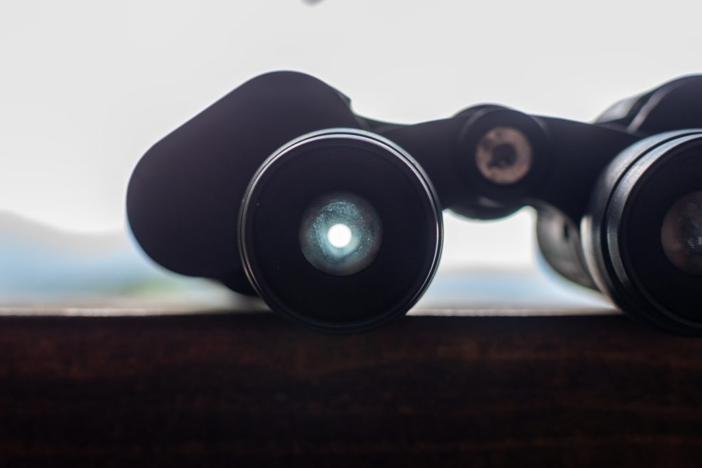 Binoculars on a fence looking at towards mountains